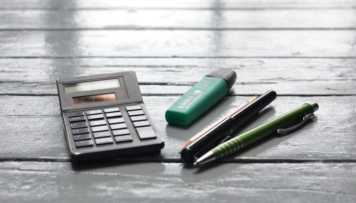 Calculator and pens on a wooden desk for preparing a price quote