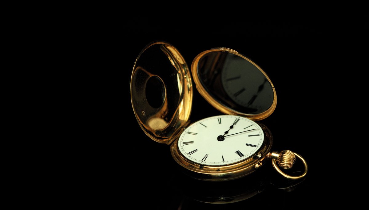 An open gold pocket watch on a dark surface